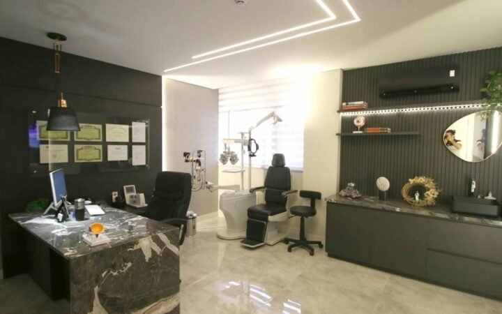 Sala de atendimento com equipamento de exame oftalmológico e mesa do médico